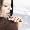 Woman brushing dandruff off her shoulder, highlighting dandruff issues in winter.
