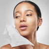 Woman using blotting paper on her cheek to get rid of oily skin