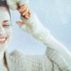 Smiling woman applying a face scrub in winter, enjoying skincare