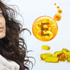 A woman displays a bottle of vitamin E oil, highlighting its role in promoting hair growth and repair
